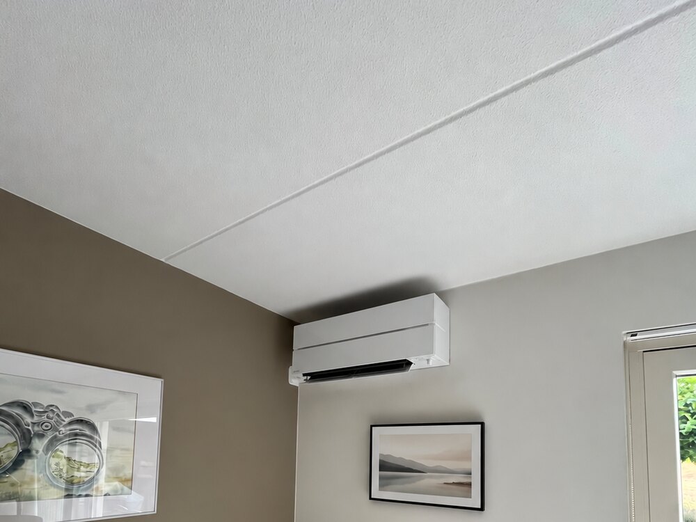 Witte wandairco in woonkamer Naaldwijk gemonteerd boven radiator